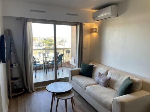 ein Wohnzimmer mit einem Sofa und einem Tisch in der Unterkunft Appartement cosy vue mer, 5min à pied de la plage, parking in Vallauris