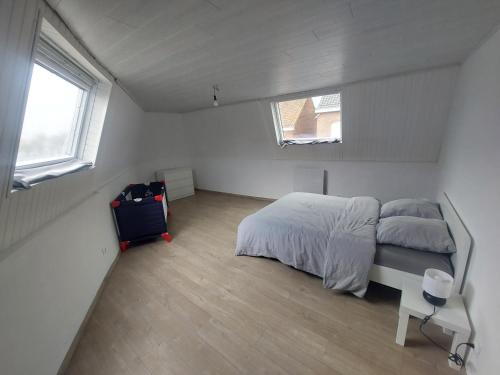 a bedroom with a bed and a suitcase and two windows at Maison en centre-ville 