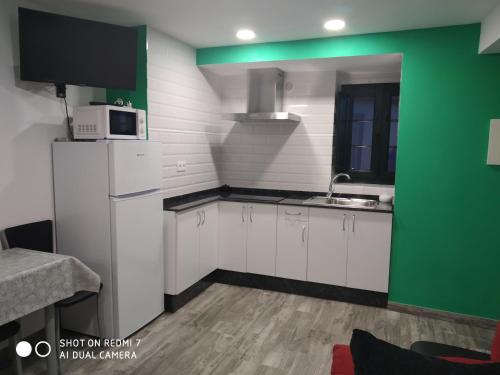 una cocina con armarios blancos y una pared verde en O RECUNCHO DE BERE, en Ribadeo