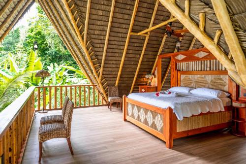a bedroom with a bed and chairs on a deck at Casa Santa Maria in Cabo Matapalo