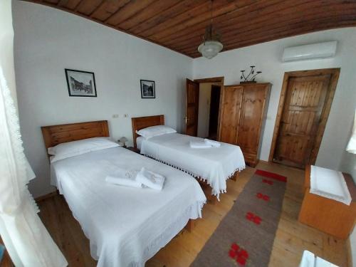 two beds in a room with white walls and wooden floors at Guest House J.Prifti in Berat