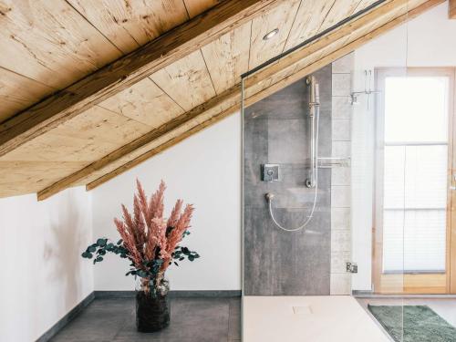 a bathroom with a shower and a vase with a plant at Wolke 9A in Traunstein