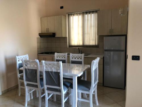 - une cuisine avec une table et des chaises blanches dans l'établissement Villa Velipoja, à Velipojë