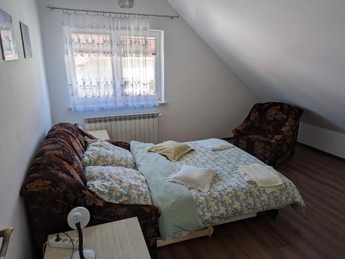 um quarto com uma cama, uma cadeira e uma janela em Apartament Osak em Stare Juchy