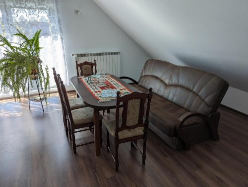 a living room with a table and a leather couch at Apartament Osak in Stare Juchy