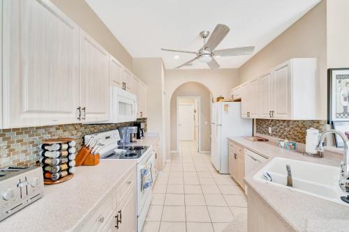 cocina con armarios blancos y ventilador de techo en Heron Glen Hideaway, en North Fort Myers