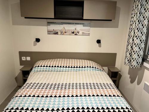 un lit dans une petite pièce avec dans l'établissement Mobilhome Luminosa tt équipé 6/8 pers, aux Mathes