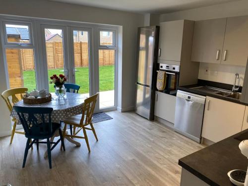 a kitchen and dining room with a table and chairs at Comfortable new home in Isleham in Ely