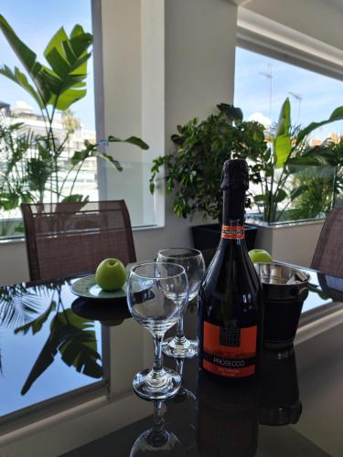 una botella de vino sentada en una mesa con copas en Carisa Deluxe Apartment With Jacuzzi, en Lárnaca