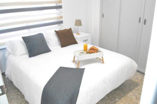 ein Schlafzimmer mit einem weißen Bett und einem Tisch darauf in der Unterkunft Light in Vila-real, central apartment with office in Villareal
