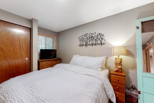 Schlafzimmer mit einem weißen Bett und einem TV in der Unterkunft Wooded Wonder in Rhododendron