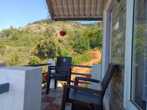 eine Veranda mit 2 Stühlen und Blick auf einen Hügel in der Unterkunft Joy House - 1 bhk Cozy entire house in Udagamandalam