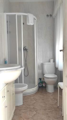 a white bathroom with a shower and a toilet at Playa en las Rías Baixas - Raxó in Raxo