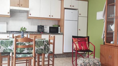 a kitchen with white cabinets and a table and chairs at Playa en las Rías Baixas - Raxó in Raxo
