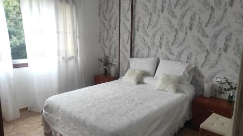 a bedroom with a white bed and a wall at Playa en las Rías Baixas - Raxó in Raxo