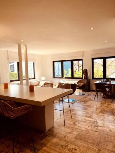 ein Wohnzimmer mit Tischen und Stühlen im Zimmer in der Unterkunft Appartement 1 chambre - LAKE SIDE HOUSE in Rixensart