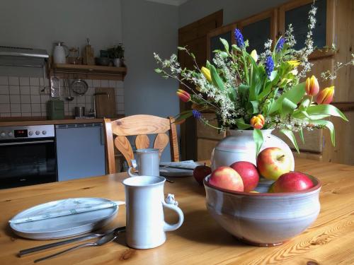stół z miską jabłek i wazonem kwiatów w obiekcie Ferienwohnung Landlust 