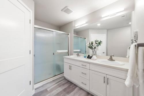 a white bathroom with a shower and a sink at Chic Apt w Jacuzzi, Pool, BBQ, & Mountain Views in Sparks