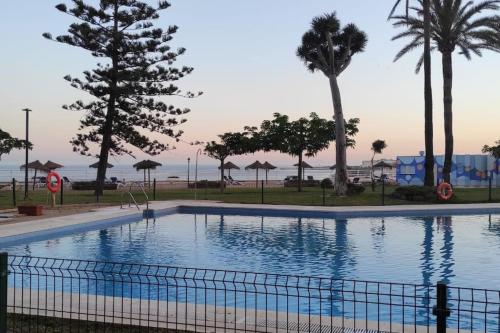 a large swimming pool with palm trees and the ocean at LOFT CASTILLO SANTA CLARA Torremolinos in Torremolinos