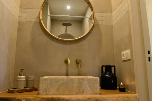een wastafel in de badkamer met een ronde spiegel erboven bij Downtown 2 BDR Apartment ***** 3 in Antwerpen