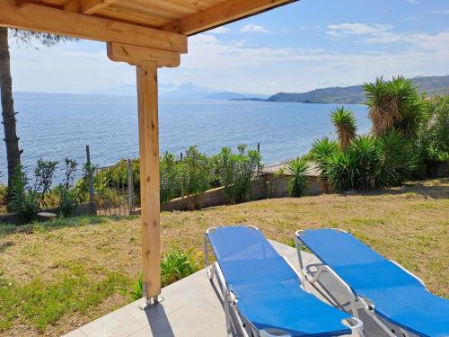 - deux chaises longues bleues assises sur une terrasse couverte donnant sur l'océan dans l'établissement Beach Studio Kotrona, à Achladi