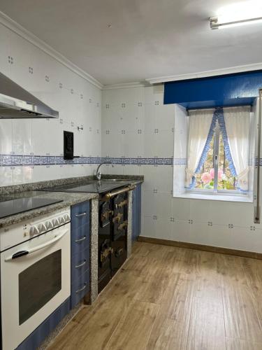 cocina con paredes azules y blancas y ventana en Casa en Treceño 5 Dormitorios y 2 Plantas, en Treceño