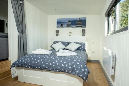a bedroom with a bed with blue and white sheets at Yew Lodge - Shepherd's Hut Railway Carriage with "Hot Tub" - Sleeps 4 - Escape Completely! in Boston