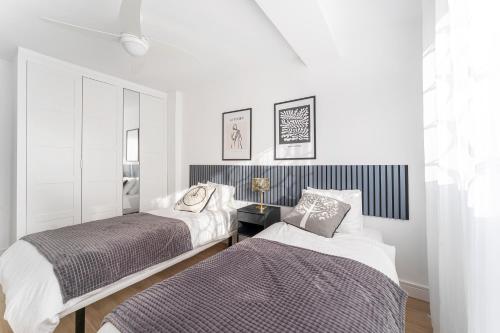 two beds in a bedroom with white walls at Espectacular piso reformado al lado del rio Turia in Valencia