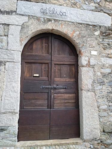 eine große Holztür in einer Steinmauer in der Unterkunft Casa Elisa apartment in Armeno