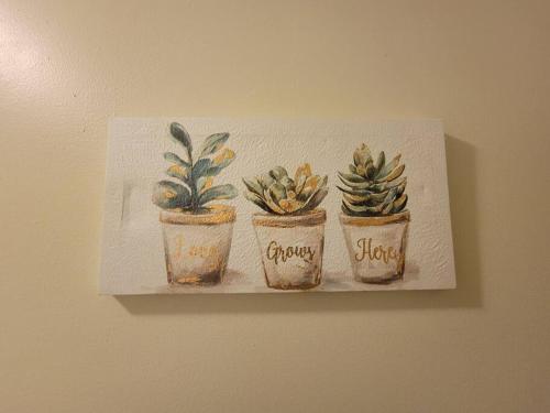 a painting of three potted plants on a wall at Lovely welcoming 3 bedroom house 