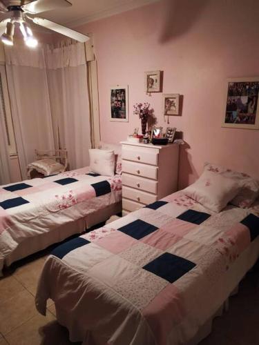 sypialnia z 2 łóżkami pojedynczymi i komodą w obiekcie Casa Mercedes w mieście Mercedes