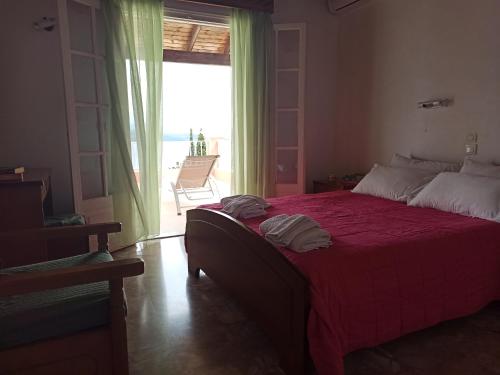 a bedroom with a large red bed with a view of the ocean at Villa Aliki in Ágios Stéfanos