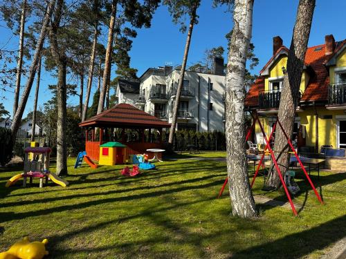 a playground in a yard with trees and a house at Dom pod Sosnami in Pobierowo