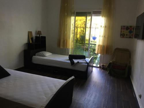 1 dormitorio con 2 camas, silla y ventana en Chambre du jardin en Rabat