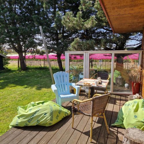 two chairs and a table on a deck with a gazebo at Vrijstaande blokhut in Egmond-Binnen