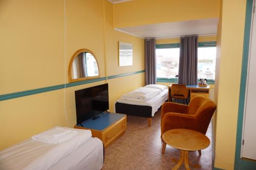 a hotel room with two beds and a chair at Verdde Hotel Lakselv in Lakselv