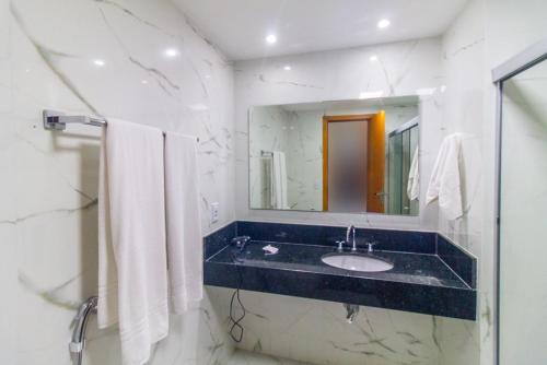 a bathroom with a sink and a mirror and towels at Garvey Park Hotel - apartamento particular 629 in Brasilia