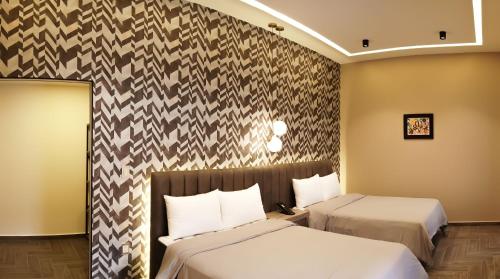 a hotel room with two beds and a wall at Hotel Capitalino in Pachuca de Soto
