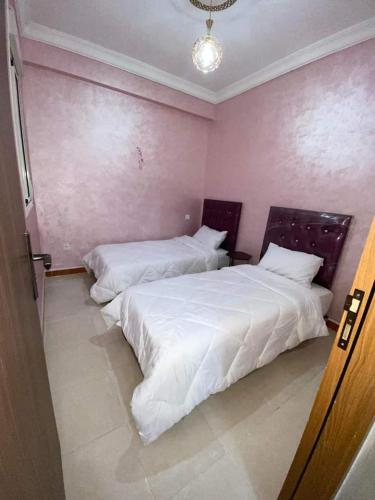 two beds in a room with pink walls at Shams doha in Beni Mellal