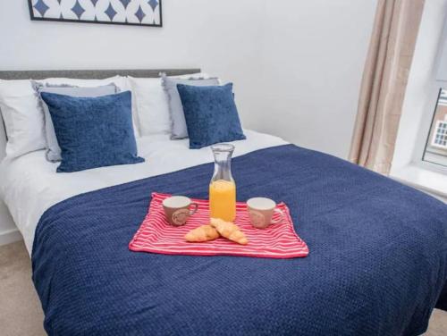 a tray with a bottle of orange juice and cookies on a bed at 1 Bedroom flat in Peterborough City centre in Peterborough