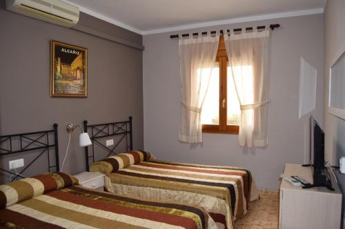 a room with three beds and a television and a window at Casa Rural Javier in Valmuel