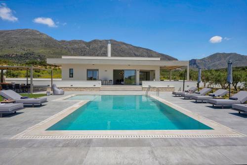 a swimming pool with lounge chairs and a house at Demar Exclusive Villa in Plakias