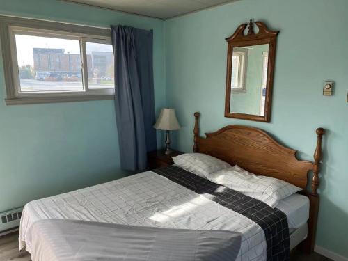 een slaapkamer met een bed met een spiegel en een raam bij Motel Sainte Catherine in Sainte-Catherine