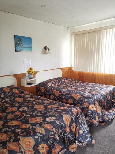 a hotel room with two beds and a window at Motel Sainte Catherine in Sainte-Catherine