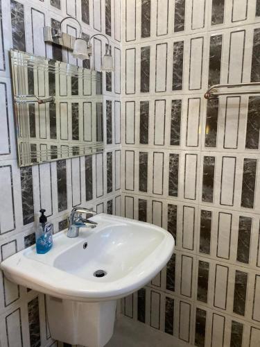 a white sink in a bathroom with black and white tiles at Jerash air apartment in Jerash