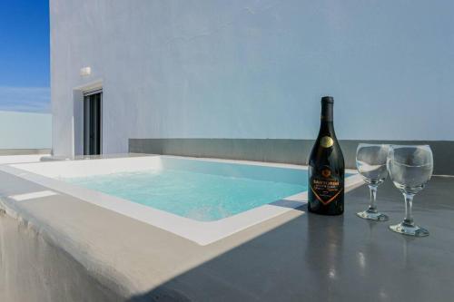 a bottle of wine and two glasses next to a hot tub at Ageri Suite in Vóthon
