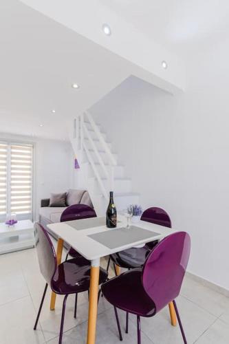 a dining room with a white table and purple chairs at Ageri Suite in Vóthon