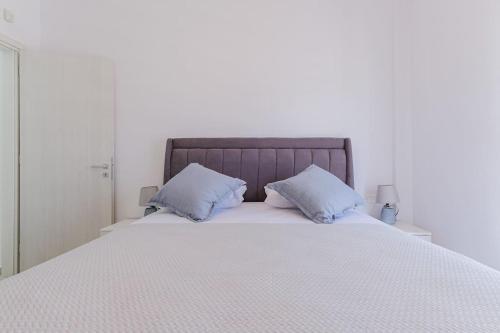 a white bed with two blue pillows on it at Ageri Suite in Vóthon