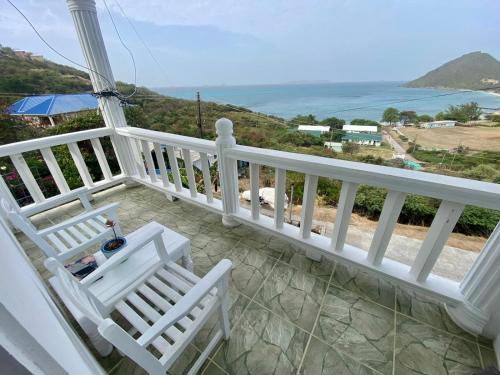 a balcony with two white chairs and a view of the ocean at Isla Vista Apartment Canouan in Canouan