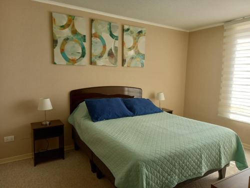 a bedroom with a bed with blue sheets and two lamps at Algarrobo Laguna Bahía Espectacular Departamento in Algarrobo